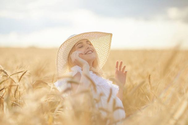 Portrait of happy woman in hat, posing in wheat field  - Fotó, kép