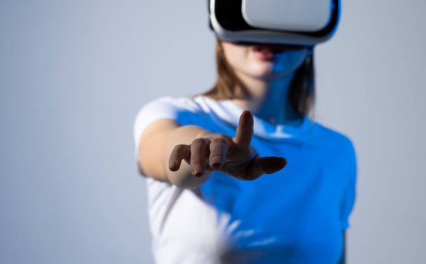 Woman using VR virtual reality glasses headset pointing at objects in metaverse. Virtual reality metaverse - Foto, Bild