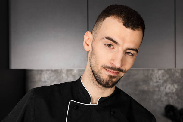 Porträt eines Kochs in schwarzer Uniform in der Küche - Foto, Bild
