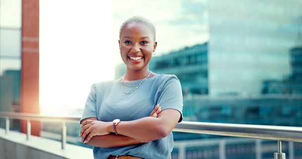 Mujer negra en la ciudad para retrato de negocios mientras feliz y brazos cruzados al aire libre con visión y orgullo. Rostro de emprendedor con edificios urbanos y motivación por los objetivos profesionales como futuro líder. - Foto, Imagen