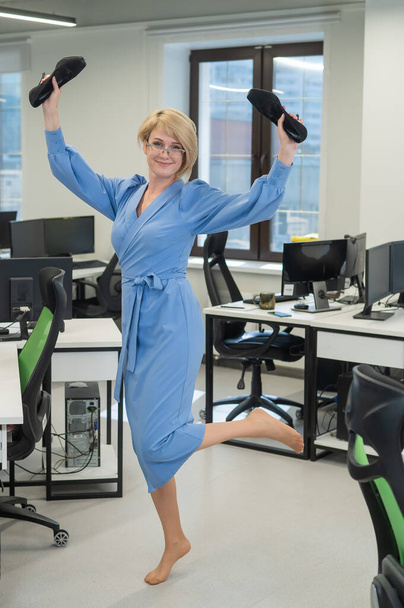 Caucasian business woman stands barefoot with shoes in her hands among the office - Foto, immagini