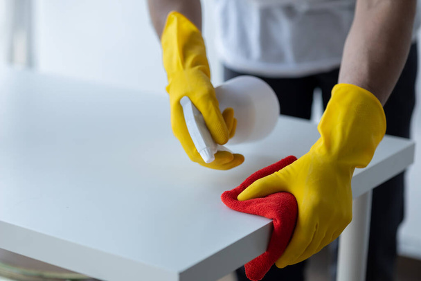 Odayı temizleyen kişi, temizlik personeli şirket odasındaki masayı silmek için dezenfektan ve bez kullanıyor. Temizlik personeli. Organizasyondaki temizliği sürdürmek. - Fotoğraf, Görsel