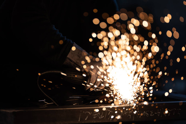 Man working on iron with grinder. Man at work. Sparkles and fire from grinder cutting. Grinder. Worker. - Photo, Image