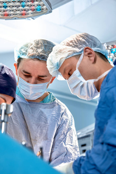 Ryhmä kirurgit tekevät leikkauksen nykyaikaisessa sairaalan leikkaussalissa, Lääkintäryhmä tekee kriittisen toimenpiteen syöpäkasvaimen poistamiseksi, taistelevat syöpää vastaan moderni lääketiede, ammattitaitoinen tiimi - Valokuva, kuva