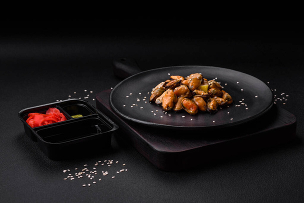 Delicious marinated mussels with spices and herbs on a ceramic plate on a dark concrete background - Foto, afbeelding