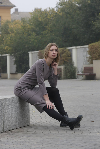 Retrato al aire libre de mujer en vestido midi gris ajustado en la ciudad, colección de moda de otoño - Foto, imagen