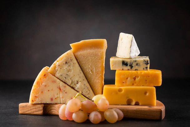 Various cheese on board on stone table - Foto, Imagen