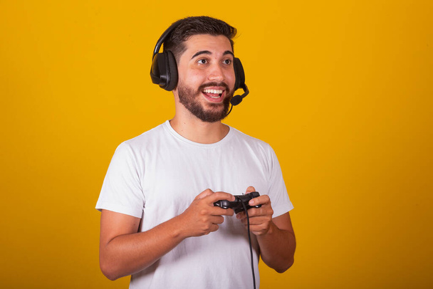 Happy Brazilian Latin American man with headset and video game controller playing - Фото, зображення
