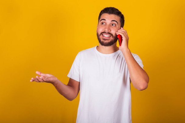 Brazilian Latin American man, talking on cell phone, conversation, smiling, communication, call, internet, applications, technology. Yellow background - Foto, afbeelding