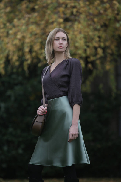 Outdoor portrait of woman in green silk satin skirt and brown blouse in the park during autumn season - Foto, Imagem