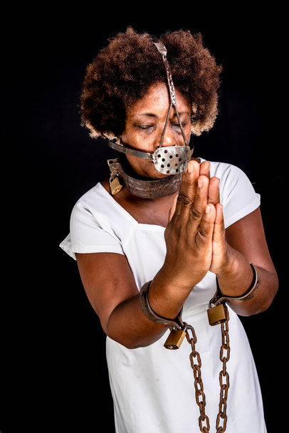 Mujer negra encadenada con una máscara de hierro en la cara, representando a la esclava Anastacia. Esclavitud en Brasil. - Foto, imagen