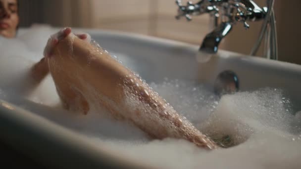 Señora despreocupada lavando las piernas en primer plano baño de espuma. Chica desnuda relajada disfrutando de la rutina de belleza descansando en un apartamento de lujo. Mujer sexy tocando la piel del cuerpo pasar tiempo en casa por la noche. Concepto de higiene - Imágenes, Vídeo