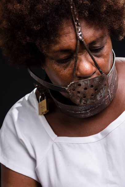 Yüzünde demir bir maske olan siyah bir kadının portresi köle Anastacia 'yı temsil ediyor. Acı ve ızdırap, işkence. Siyah arkaplana karşı. - Fotoğraf, Görsel