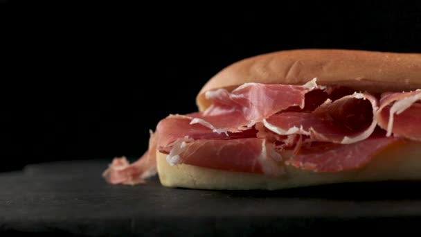 сэндвич с нарезанной испанской ветчиной из иберико на черной деревянной доске - Кадры, видео