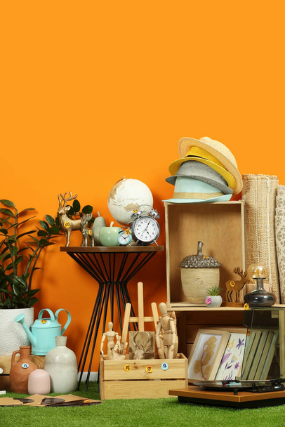 Many different items near orange wall in room. Garage sale - Фото, изображение