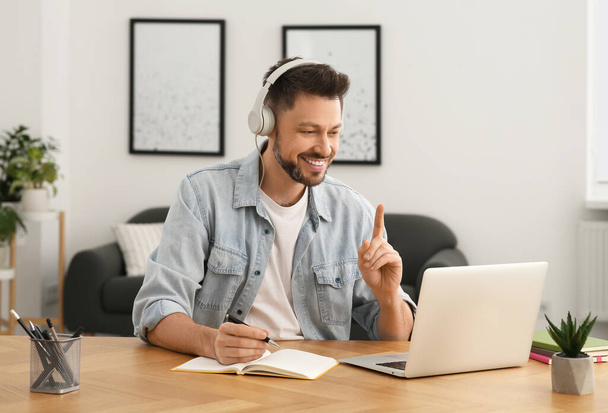 Man in headphones studying on laptop at home. Online translation course - Foto, Imagem