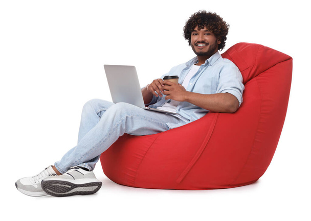 Smiling man with laptop sitting on beanbag chair against white background - Fotografie, Obrázek