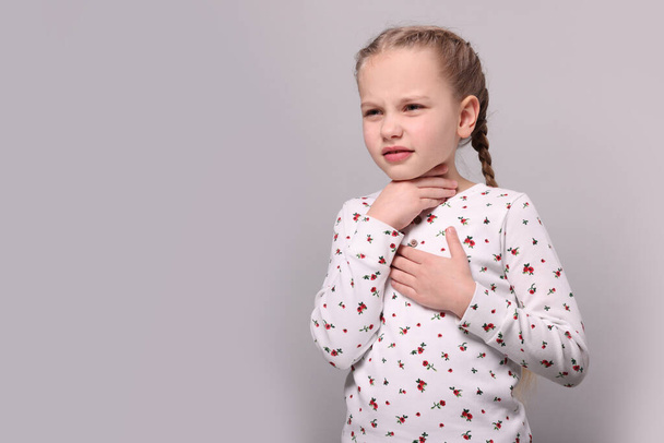 Girl suffering from sore throat on light grey background. Space for text - Foto, afbeelding