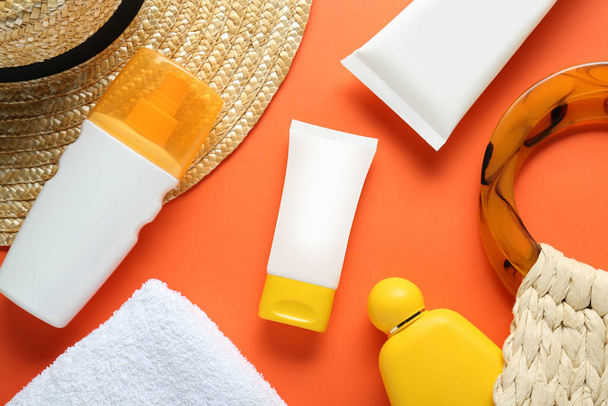 Suntan products, straw hat and bag on orange background, flat lay - 写真・画像