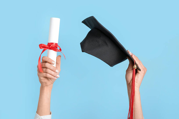Mujer con sombrero de graduación y diploma sobre fondo azul - Foto, Imagen