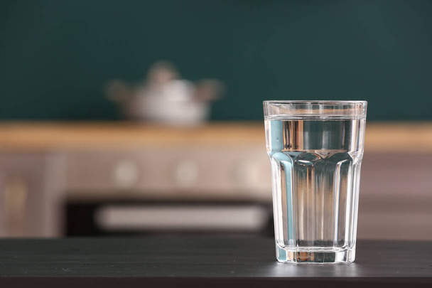 Glass of water on black table in kitchen - Photo, image