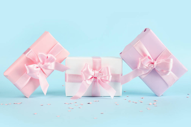 Gift boxes with beautiful bows and confetti on blue background - 写真・画像