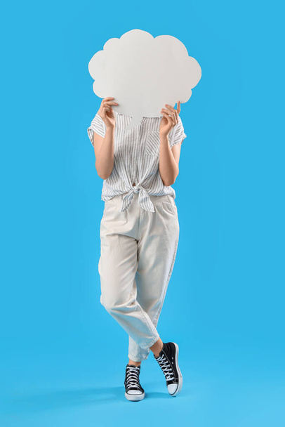 Young woman hiding face behind blank speech bubble on blue background - Fotoğraf, Görsel