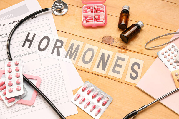 Word HORMONES avec des pilules et des fournitures médicales sur fond en bois - Photo, image