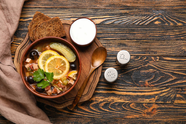 Egy tál ízletes Hodgepodge leves tejföllel és kenyérrel fa alapon - Fotó, kép