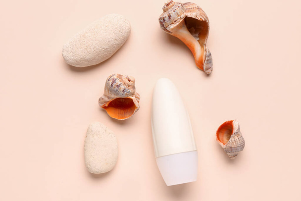 Deodorant s mušlemi a kameny na béžovém pozadí - Fotografie, Obrázek