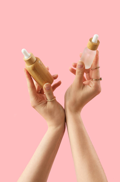 Hände mit Kosmetikprodukten auf rosa Hintergrund - Foto, Bild