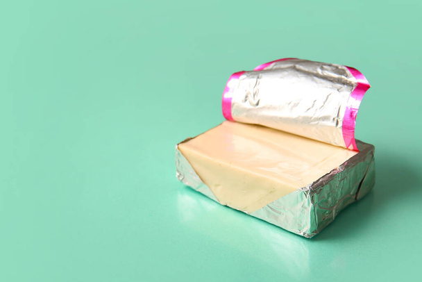 Processed cheese in foil on turquoise background - Valokuva, kuva