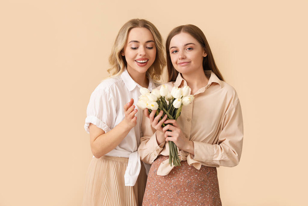 Jovens irmãs com tulipas em fundo bege - Foto, Imagem