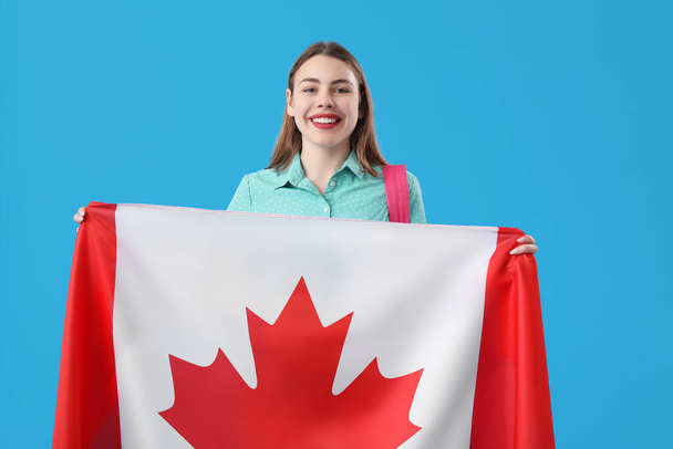 Jonge vrouw met vlag van Canada op blauwe achtergrond - Foto, afbeelding