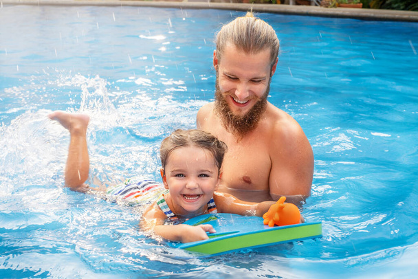 Το παιδί μαθαίνει να κολυμπάει στην πισίνα με τον μπαμπά. - Φωτογραφία, εικόνα