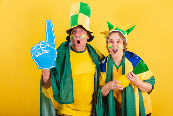 adult couple, soccer fan from brazil, wearing flag and hat. vibrating, wow, incredible. - 写真・画像