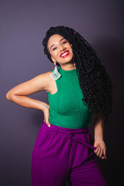 Beautiful Brazilian black woman, dressed in green and purple. Half body portrait, gray infinity background. - Foto, Imagem