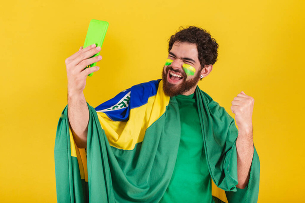 caucasian man with beard, brazilian, soccer fan from brazil, taking self portrait with cellphone, selfie, smartphone. - Φωτογραφία, εικόνα