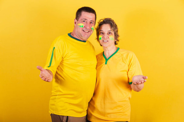 adult couple, soccer fans from brazil isolated on yellow - Фото, зображення