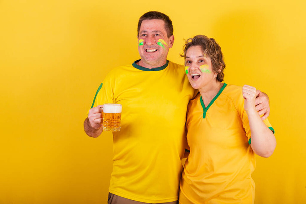 volwassen stel, voetbal fans van braziliaans geïsoleerd op geel - Foto, afbeelding