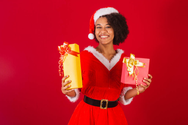 beautiful black brazilian woman, dressed as santa claus, mama claus, holding two gifts - 写真・画像