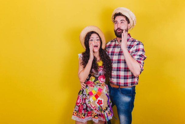 Beautiful couple dressed in typical clothes for a Festa Junina. Arraia de Sao Joao. Calling and screaming loudly, promotion. - Foto, Bild