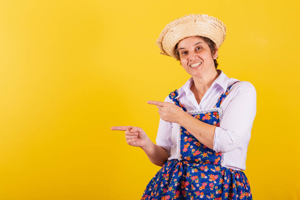Mature woman dressed in typical Festa Junina clothes. Pointing to negative space, product, promotion, advertisement. - Фото, зображення