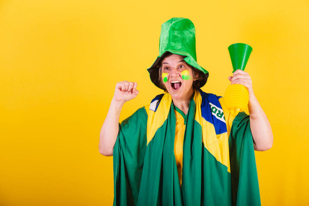 adult adult woman, soccer fan from brazil, wearing flag and hat, using horn noise, cheering. - Foto, afbeelding