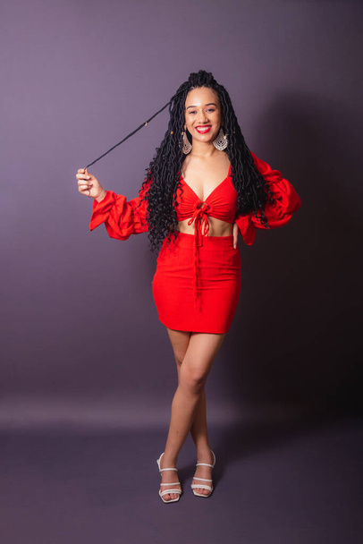 Beautiful black Brazilian woman, dressed in red. Full length portrait, infinite background. - 写真・画像