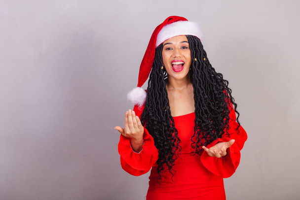brazilian black woman, wearing christmas clothes, merry christmas, smiling, calling with hands, inviting. - 写真・画像