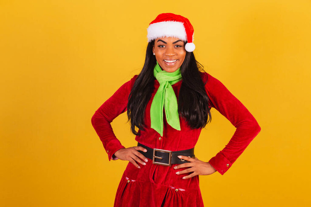 Beautiful black Brazilian woman, dressed in Christmas clothes, santa claus, with hands on her hips. - Foto, imagen