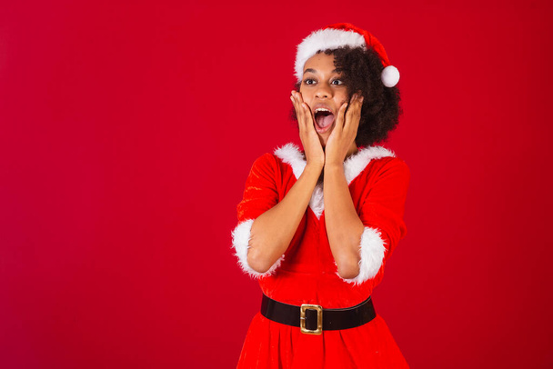 beautiful black brazilian woman, dressed as santa claus, mama claus, hands on face, incredible - Photo, Image