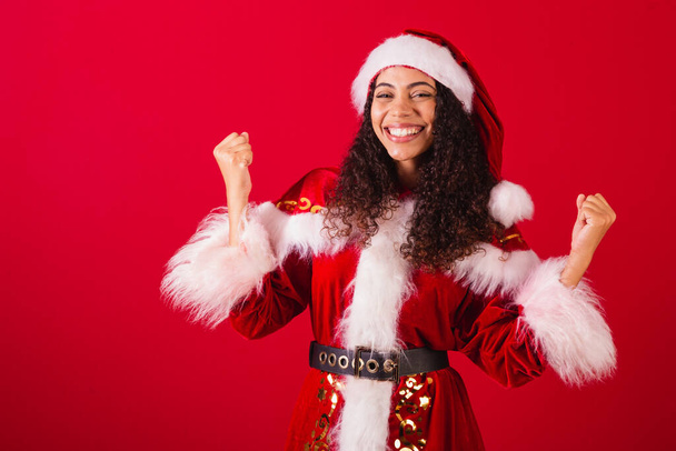 beautiful brazilian black woman, dressed as santa claus, christmas clothes. celebrating, vibrating in happiness. - Foto, imagen