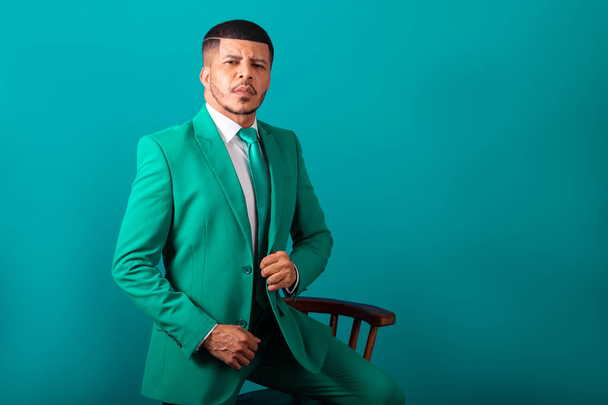 Brazilian black man, dressed in suit and green tie, Businessman. posing with wooden bench - Fotografie, Obrázek